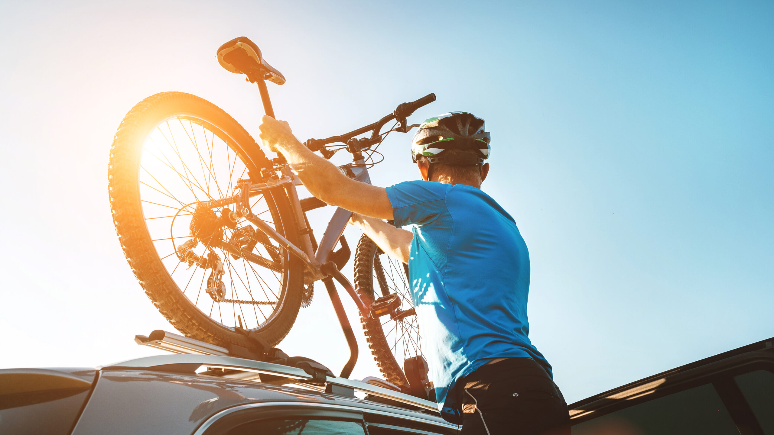 Mountain biker man take of his bike fron the car roof